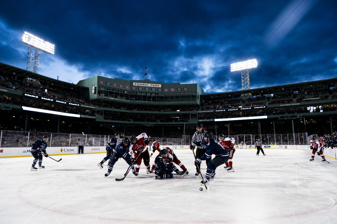 Multiple hockey players playing on an ice skating rink. 