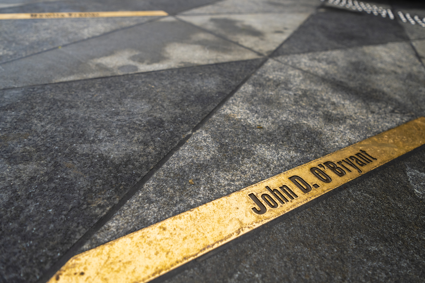 The name "John D. O'Bryant" is shown etched in gold stone on the ground