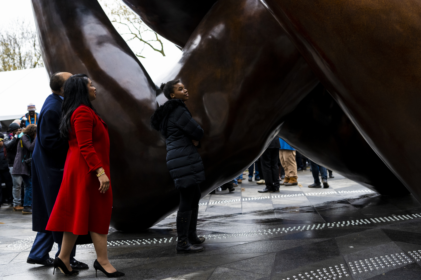 three people admire the embrace statue