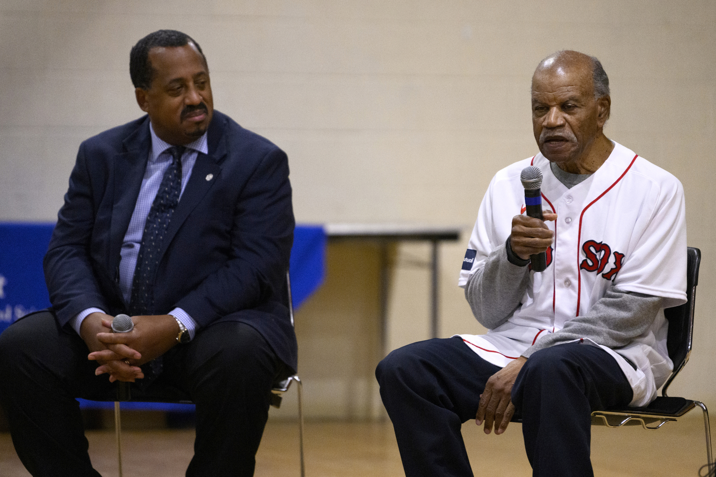 person wearing red sox jersey speaking into microphone