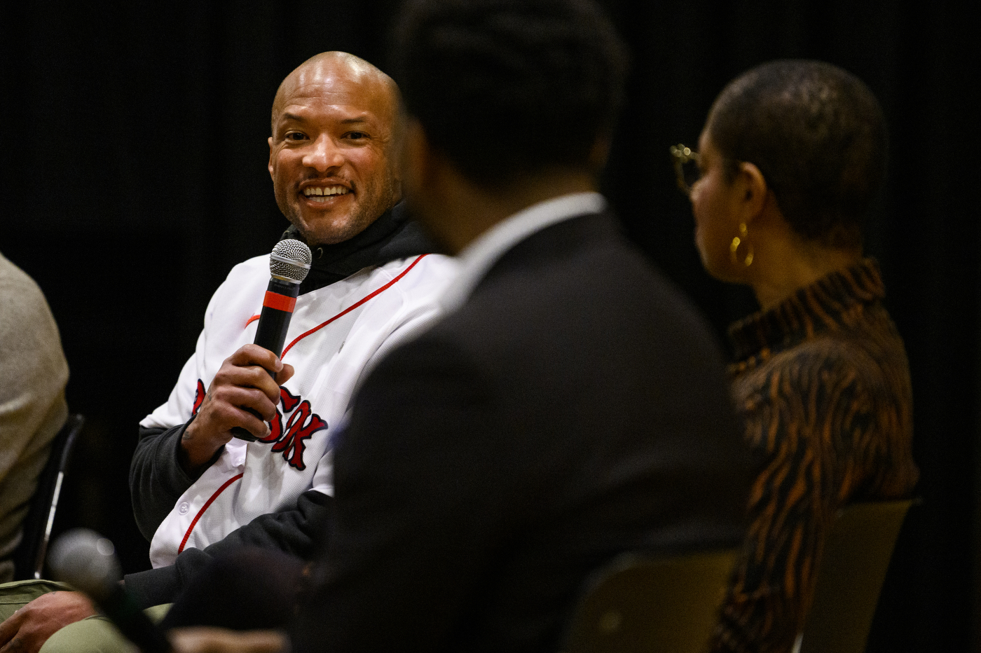 person wearing red sox jersey speaking into microphone