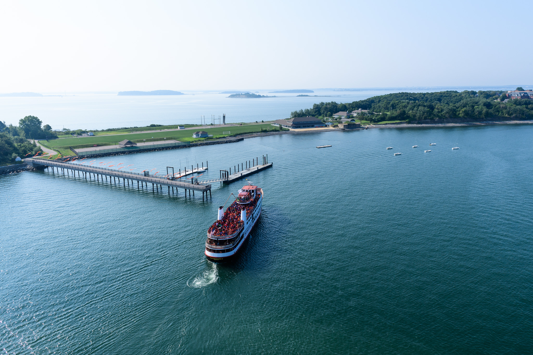 A ferry full of people in matching shirts heading towards Camp Harbor View