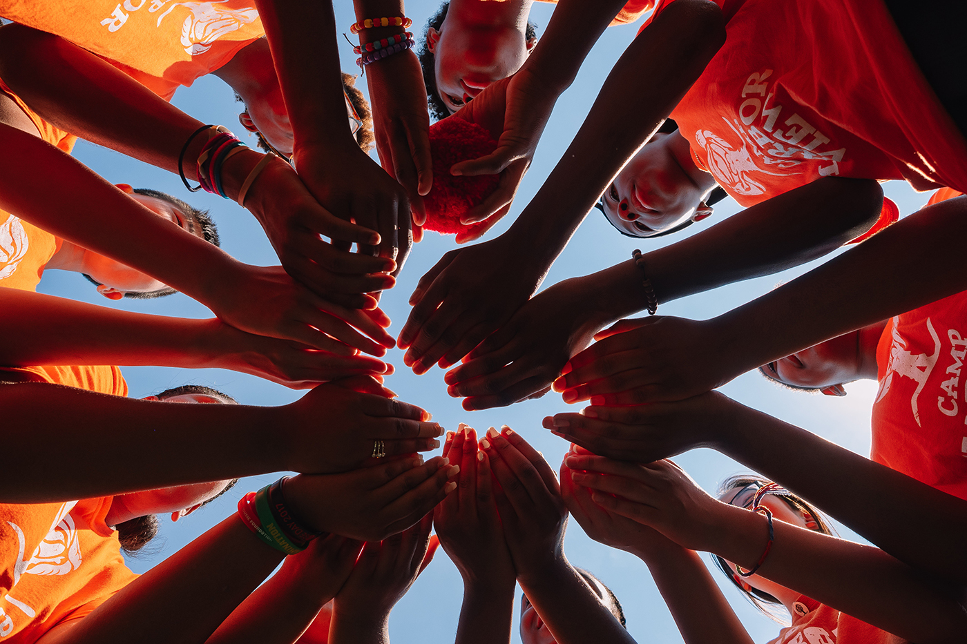 Children at Camp Harbor View in a circle with their hands in the middle