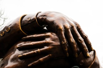 A close up of 'The Embrace' sculpture that focuses on two hands overlapped with one another