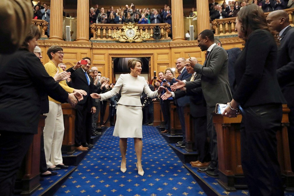 maura healey shaking hands as she walks down the aisle of the house of chambers