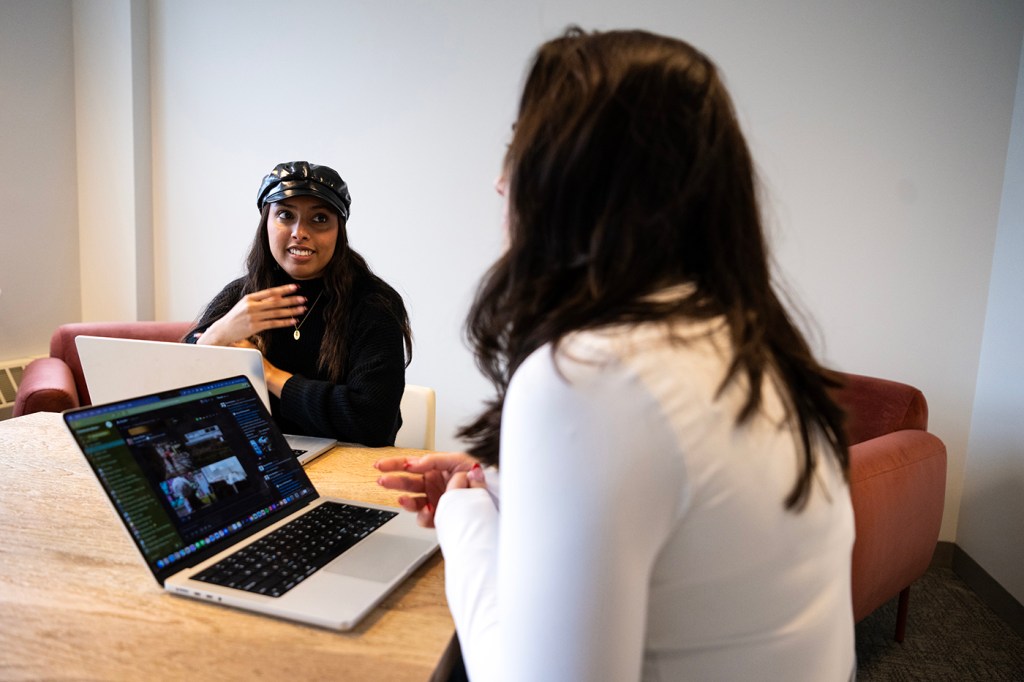 two people having a conversation at a table with their laptops open