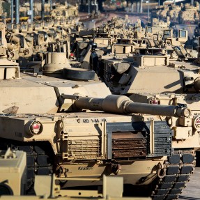 soldier walking past a line of tanks