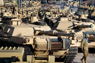 soldier walking past a line of tanks