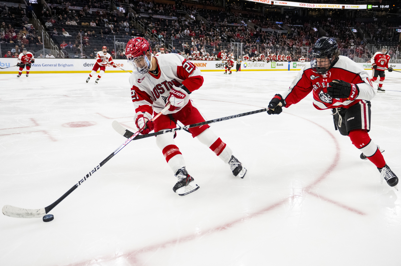 northeastern hockey player chases a boston university player on ice