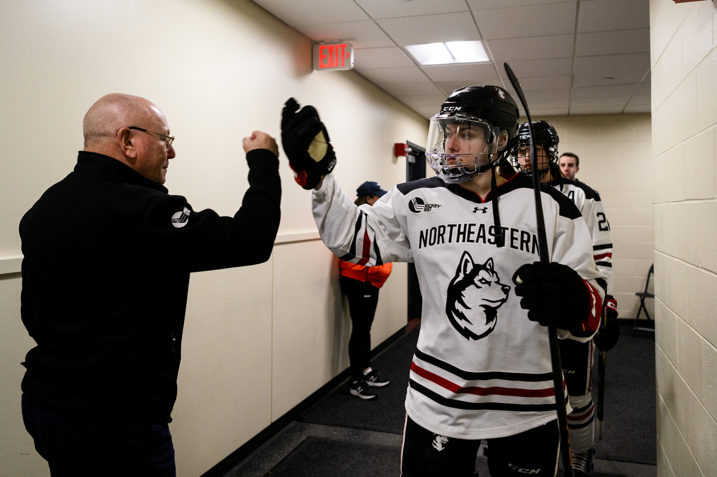 northeastern hockey player fist bumping hockey coach