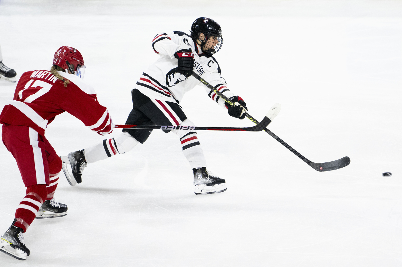 northeastern womens hockey player passing the puck