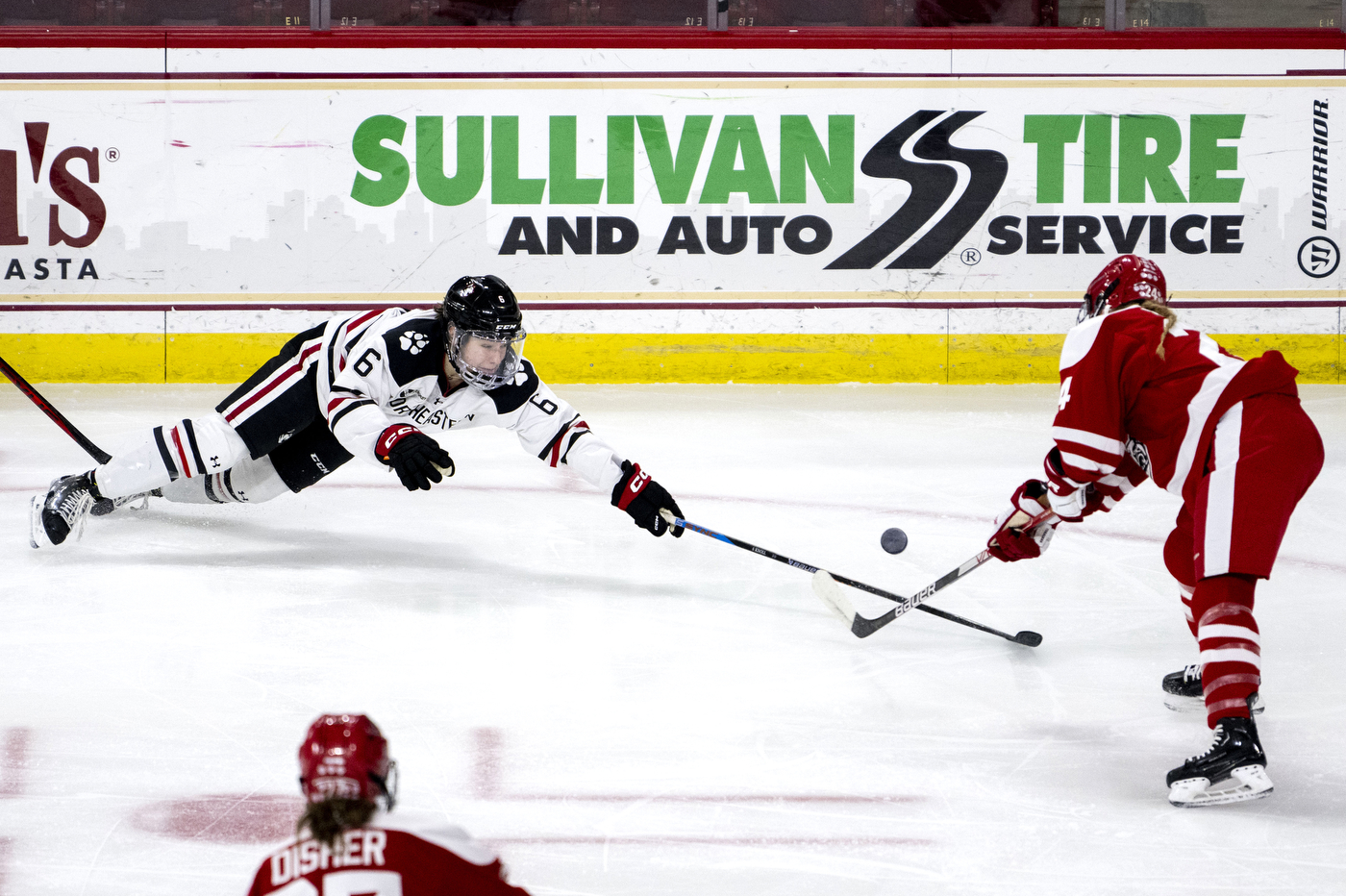 northeastern womens hockey player falling towards puck