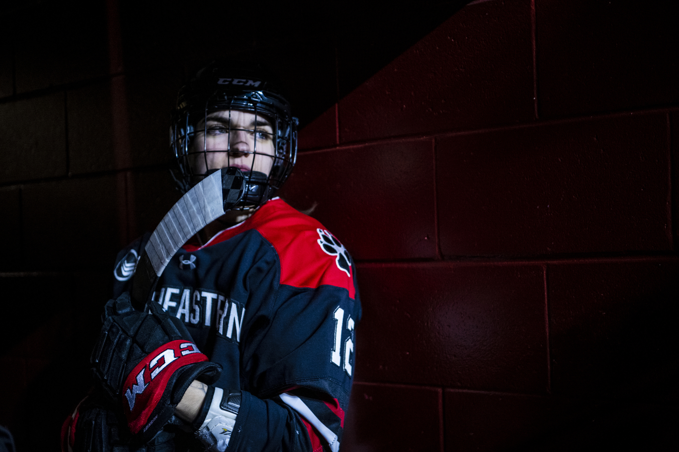 A hockey player wearing a helmet and face mask holds a hockey stick