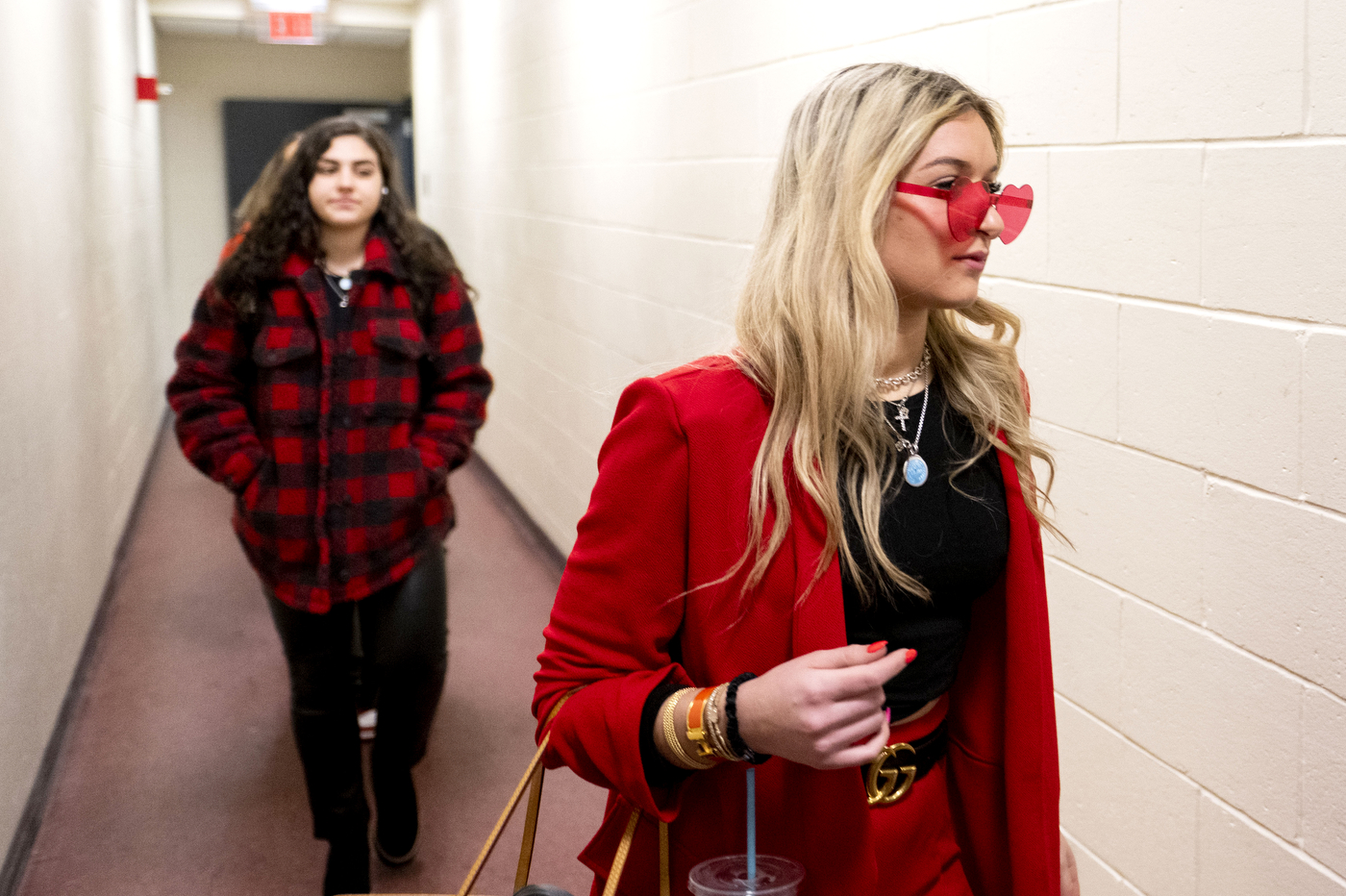 Two Northeastern women's hockey players walk down a hallway outside a locker room