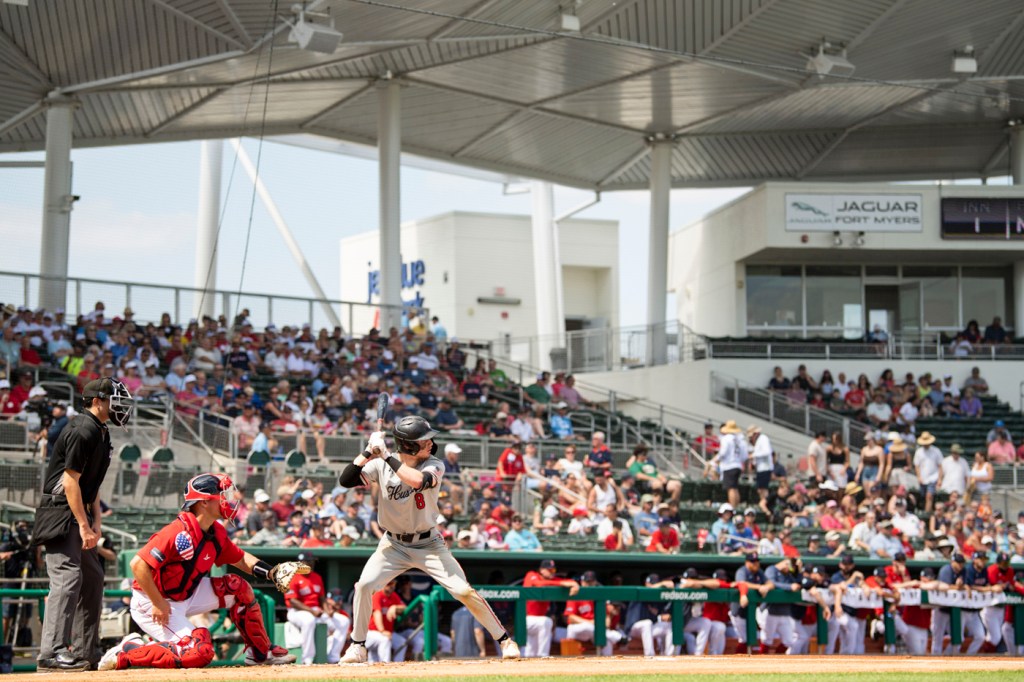 A Northeastern baseball player is at bat. The stands behind him are full of fans.