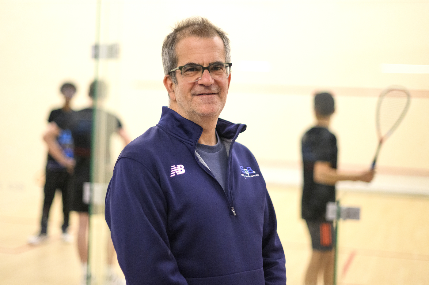 headshot of Greg Zaff inside squash court at SquashBusters