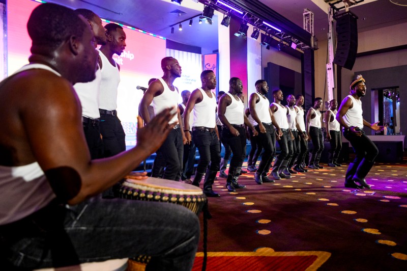 group of people in white tank tops and black pants dancing on stage