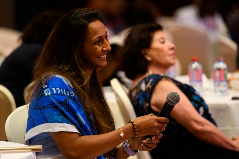 person holding microphone and smiling at leadership summit