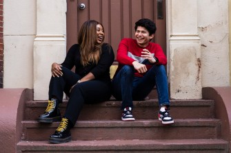 two students sitting on the steps of a building laughing together