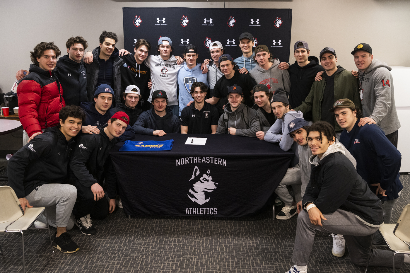 Northeastern mens hockey team posing with Devon Levi