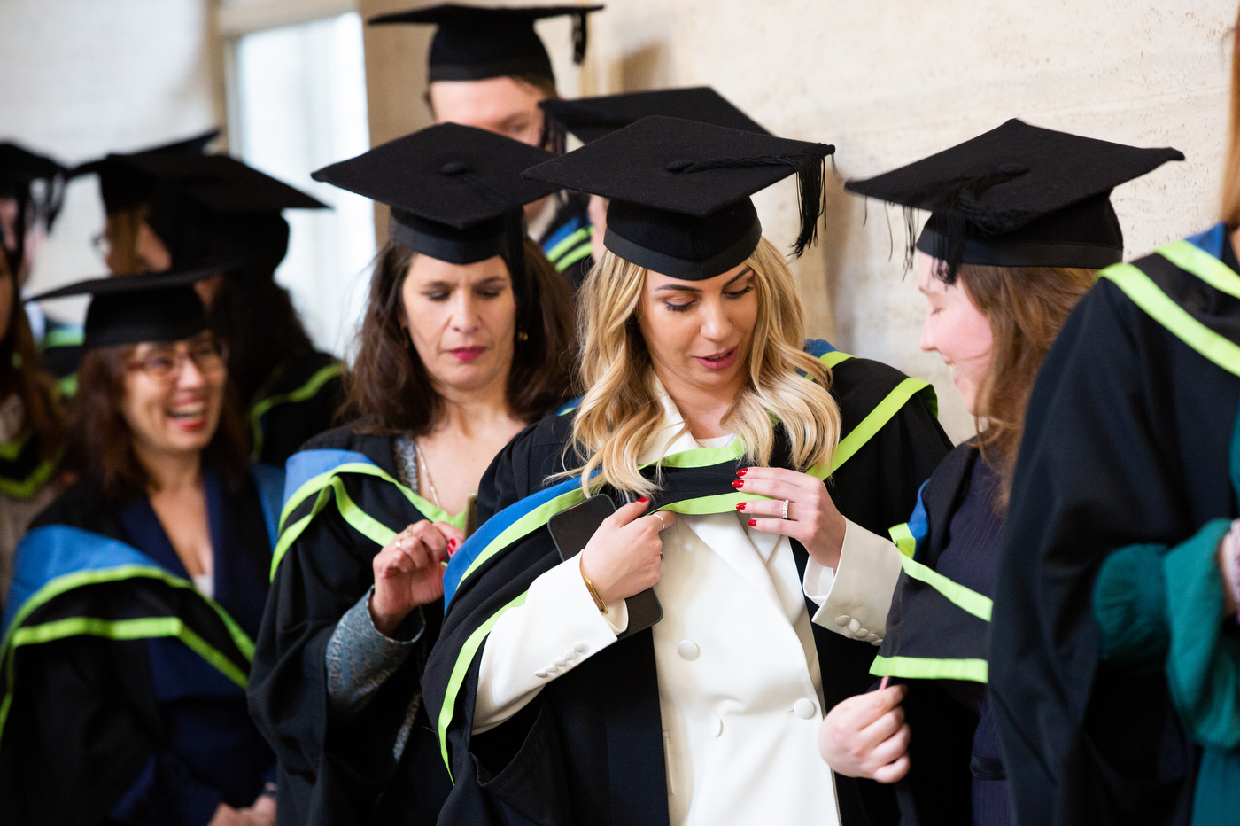 student fixing cap and gown at graduation