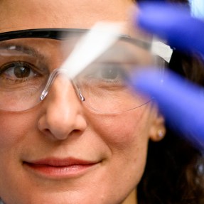 Rebecca Carrier wearing safety goggles holding up a lab sample