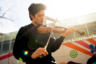 Joe de Georgeo plays the fiddle in front of a mural.