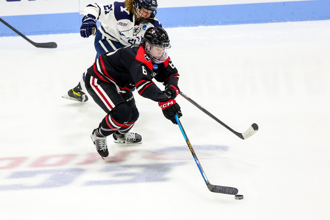 northeastern womens hockey player skating down the rink with the puck