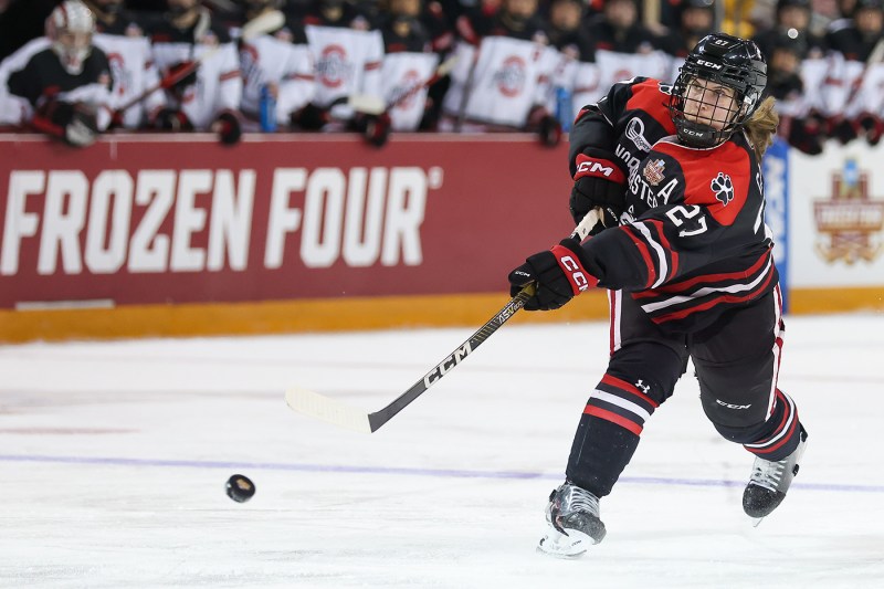 northeastern womens hockey team player shooting the puck