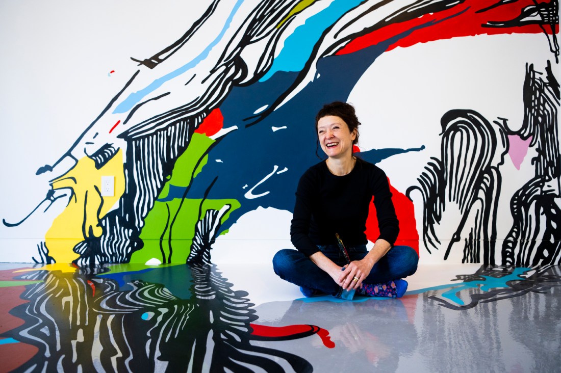Sophia Ainselle posing for a portrait in front of a mural. 
