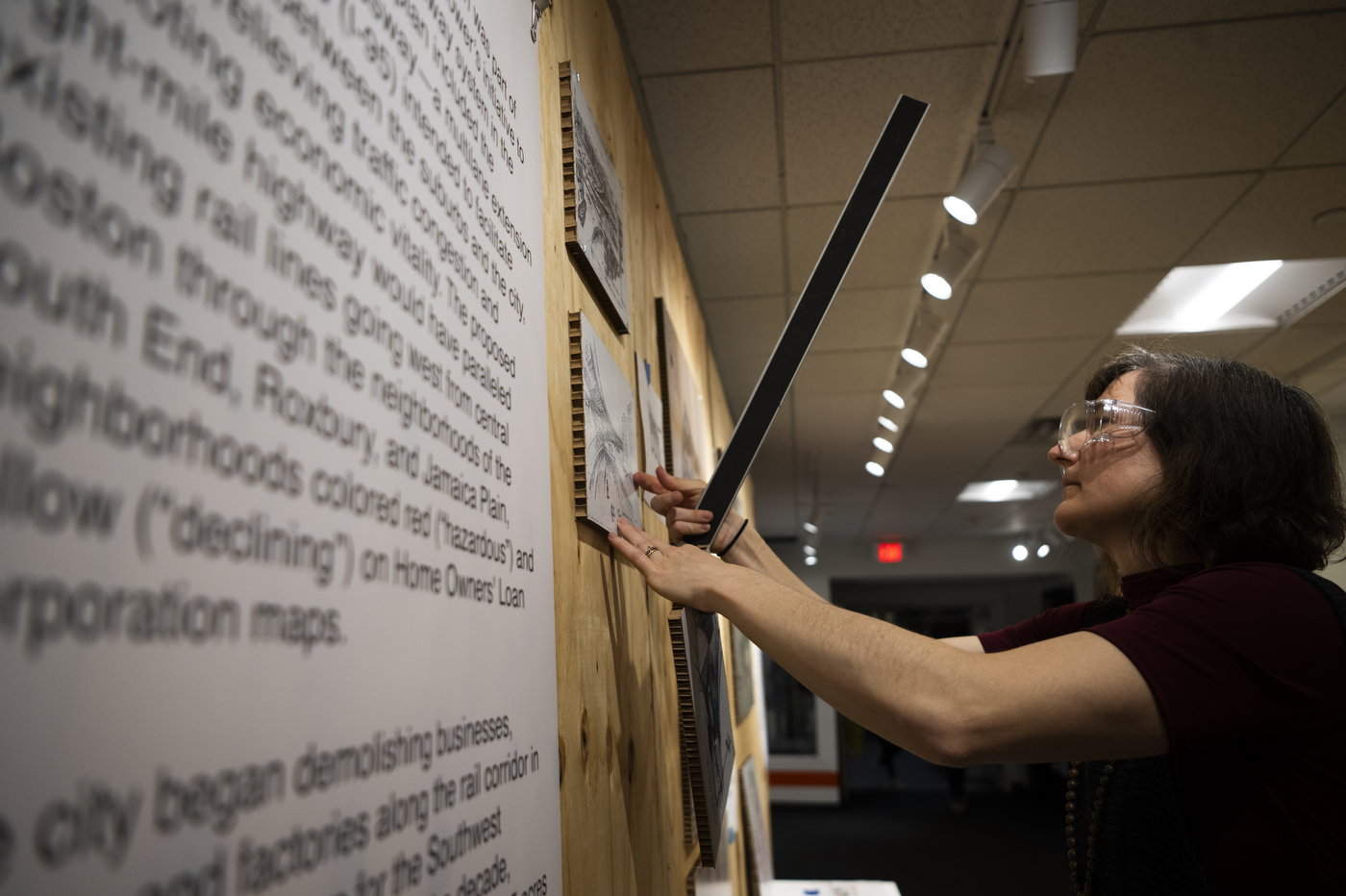 Mary Hale hanging a piece of artwork for Ruggles Station exhibit