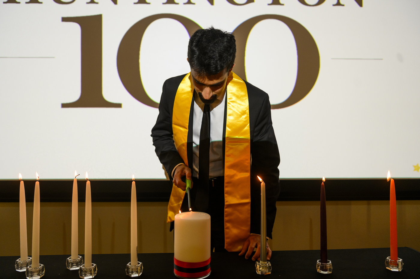 a person stands on stage lighting a candle