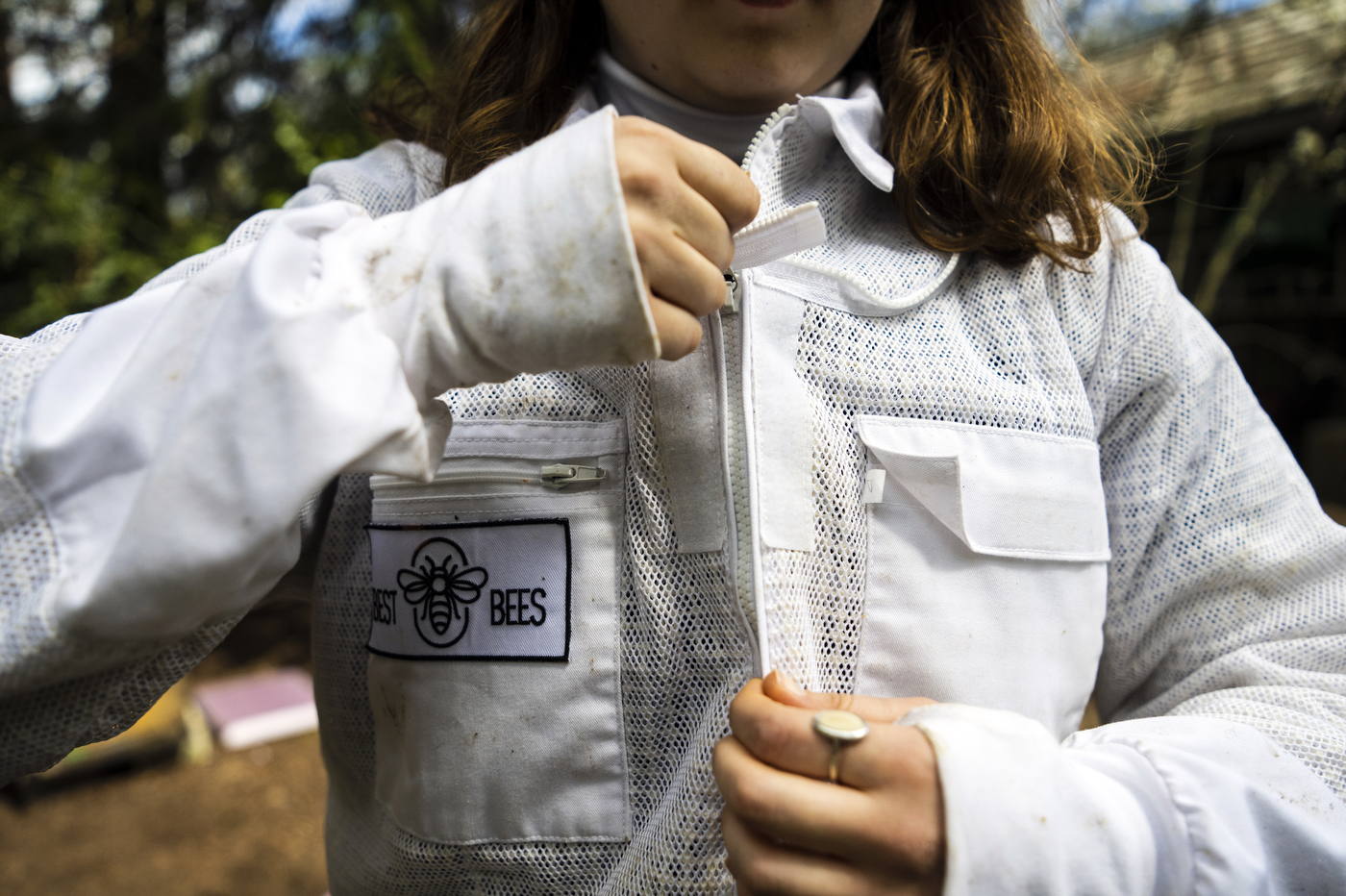 Katherine Antos zips her beekeeper suit.