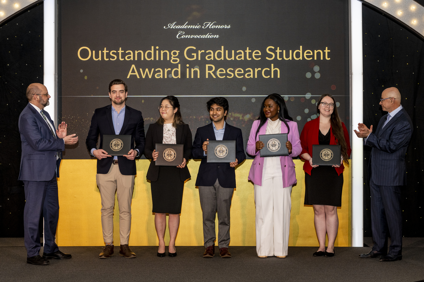 Seven people stand together with multiple awards at Northeastern's Annual Academic Honors Convocation.