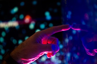 Hand reaching out to touch mirror with iridescent background