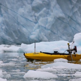 A boat travels past melting icebergs.