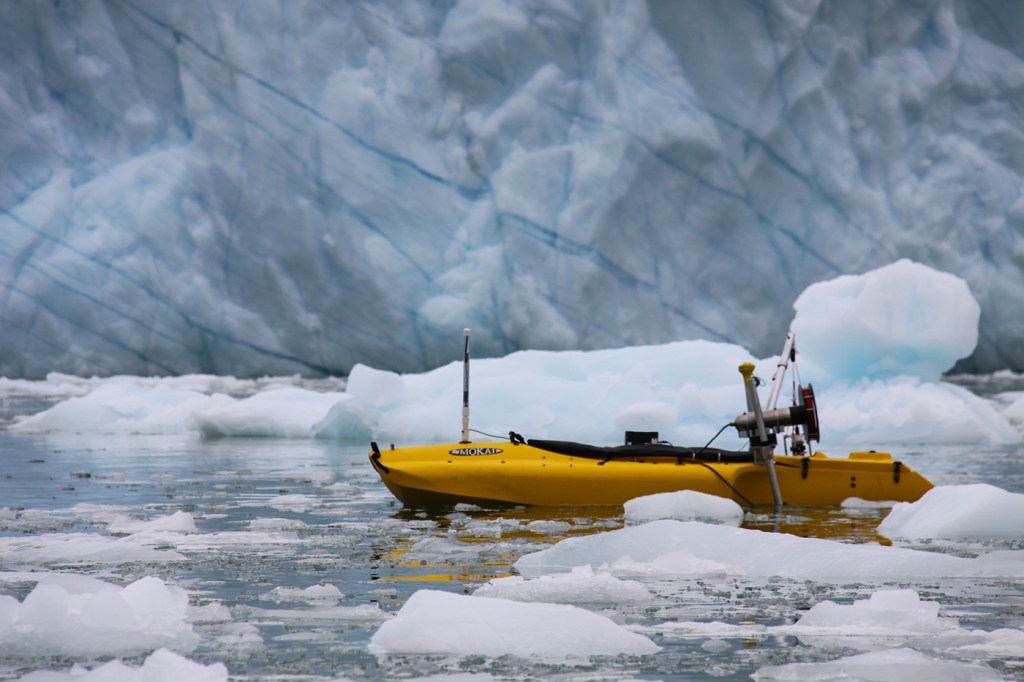 A boat travels past melting icebergs.