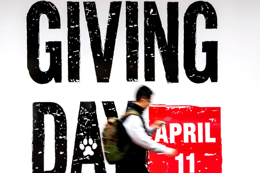 A student walks past a Giving Day sign outside the Curry Student Center.