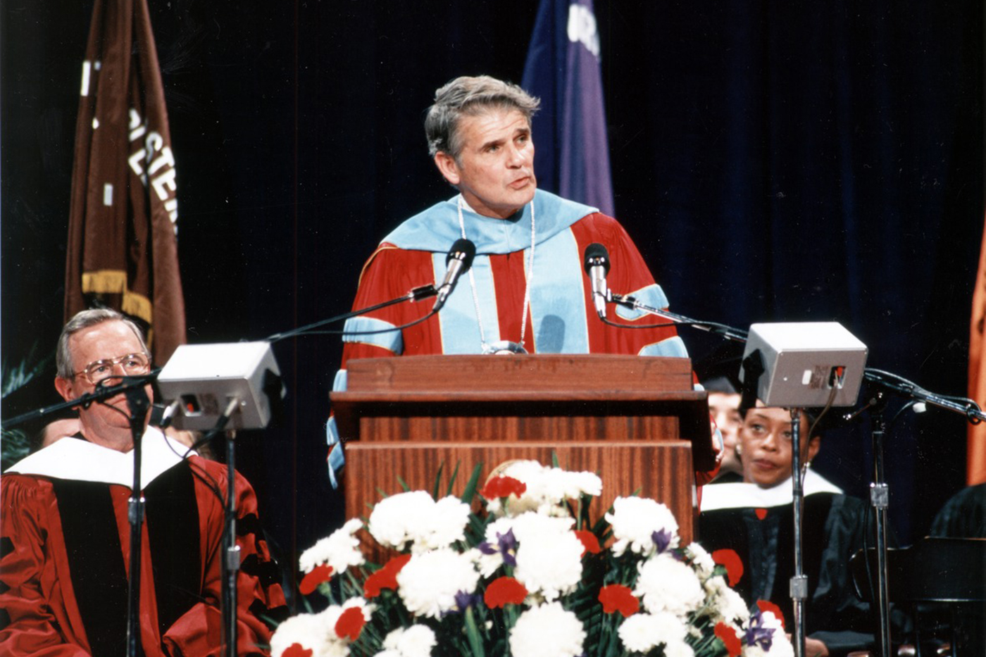 John Curry speaking at a podium. 