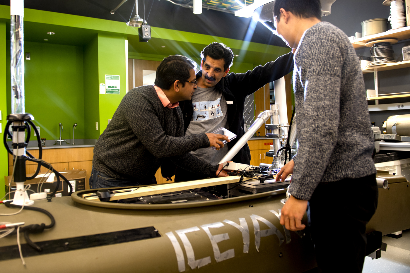 Three people work to measure how quickly icebergs are melting in a laboratory.