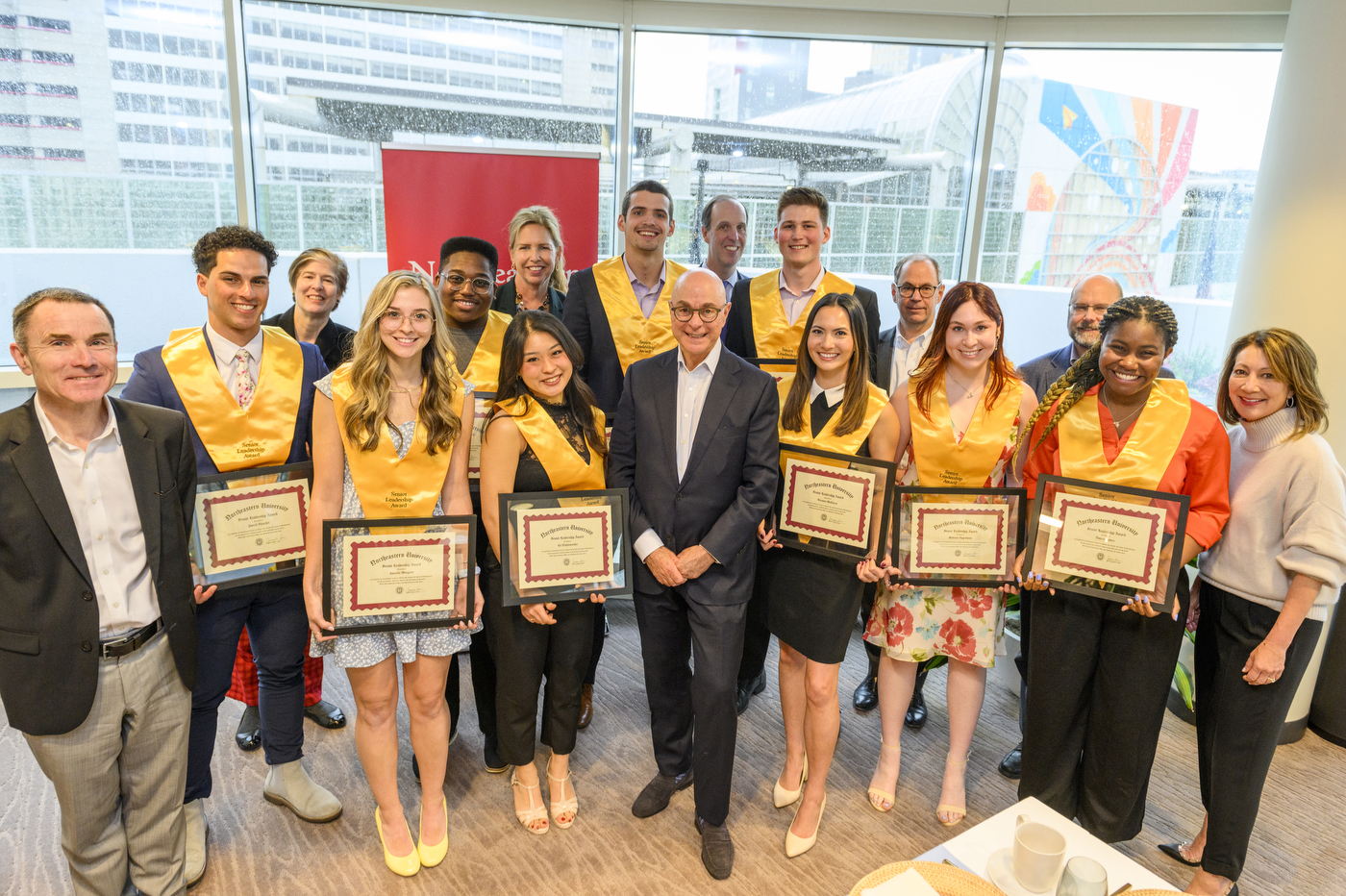 students with gold "Senior Leadership Award" sashes posing for a group photo with President Aoun and several other university leaders