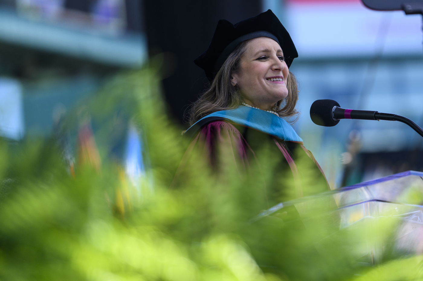 A woman in Commencement regalia speaks into a microphone.