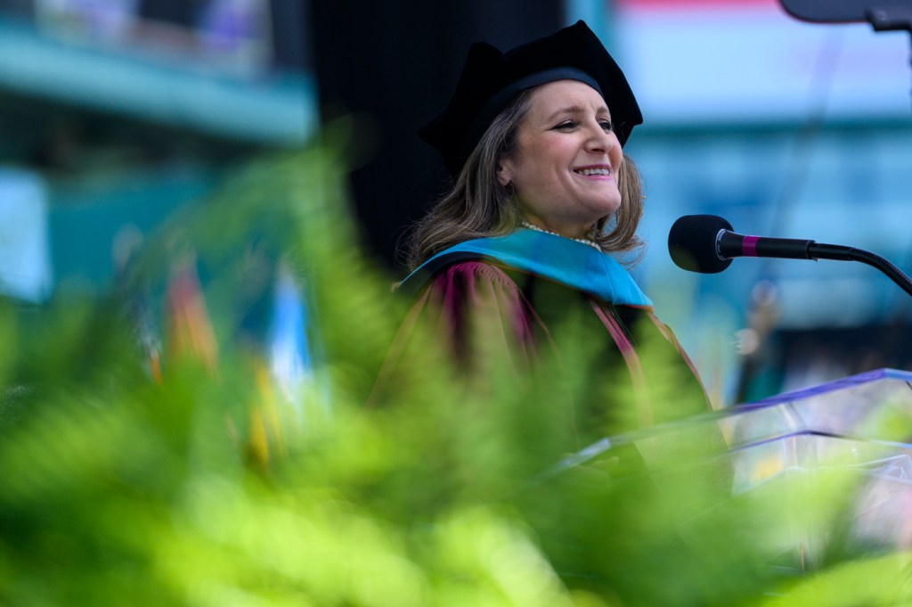 A woman in Commencement regalia speaks into a microphone.