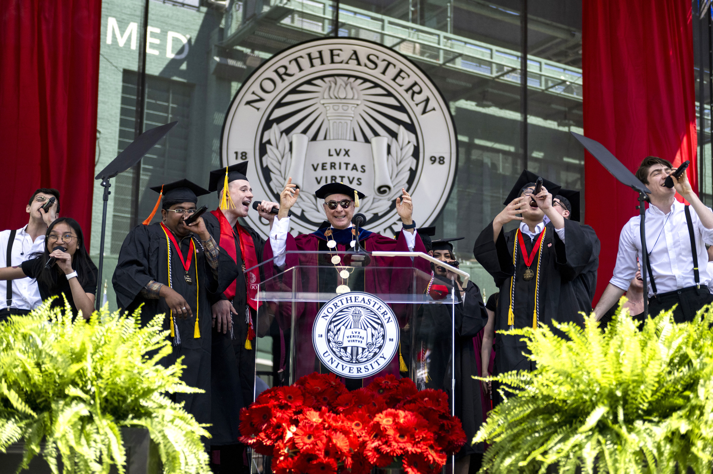 President Aoun at the podium, surrounded by singing graduates.