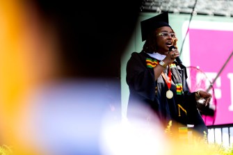 Chinma Nnadozie-Okananwa reciting her poem into a mic at commencement