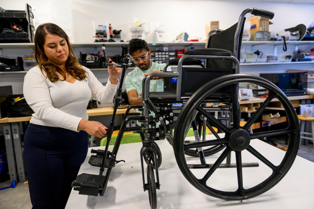 Priyanka Jalan attaching camera mount to wheelchair