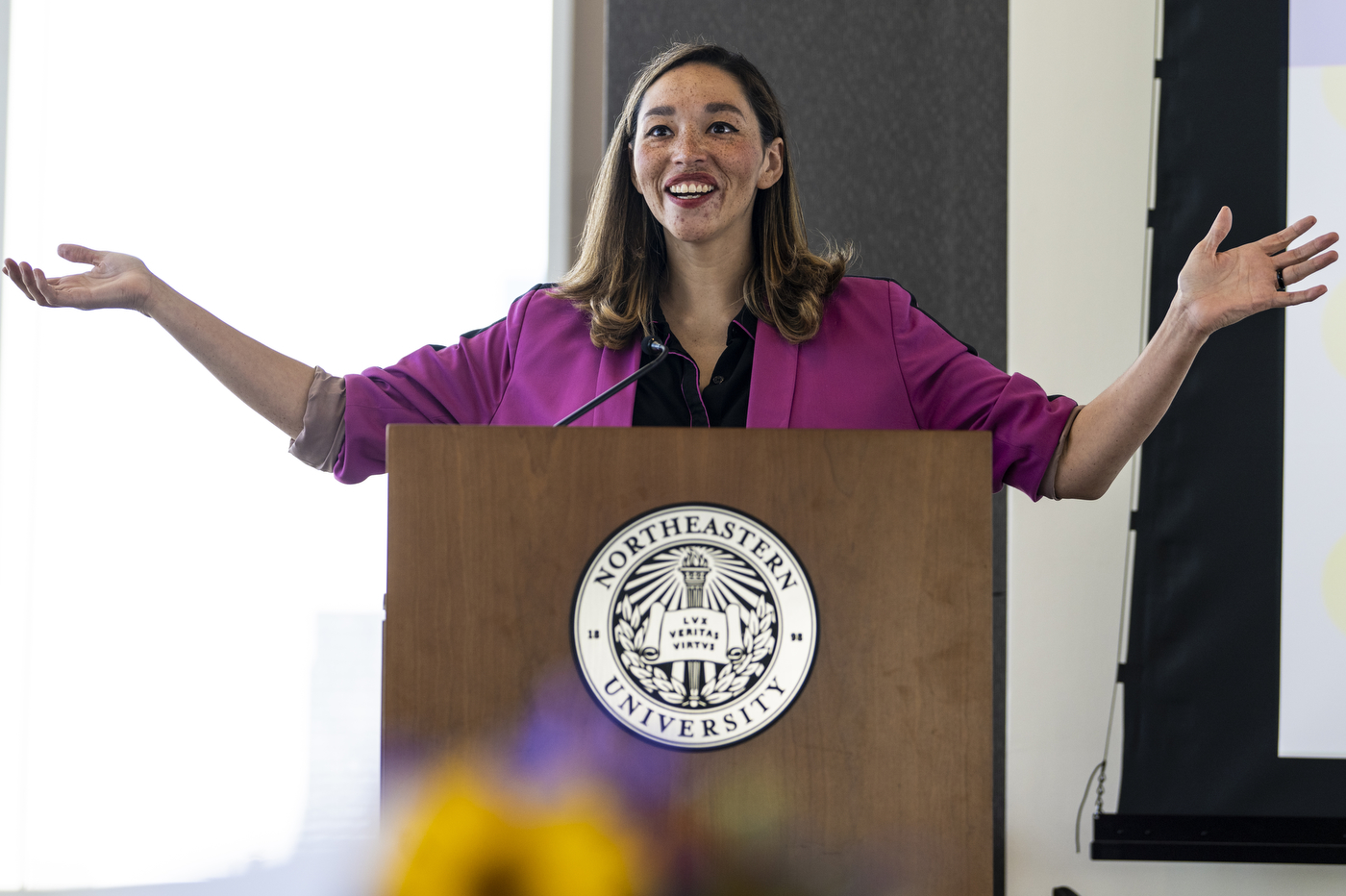 All Raise team member speaking into microphone and gesturing with both hands