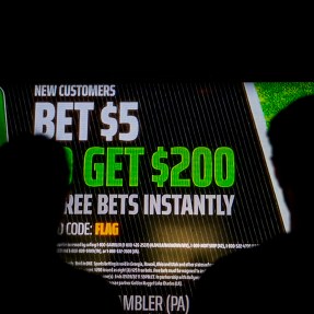 Silhouette of two people looking at a sports betting ad