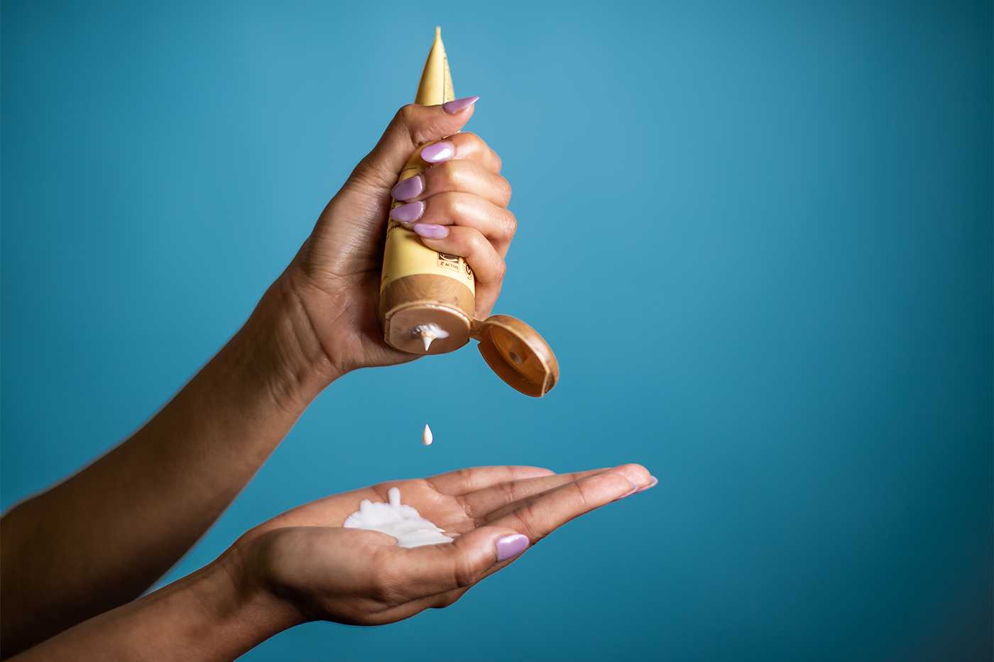 person squeezing tube of sunscreen into their hand