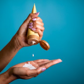 person squeezing tube of sunscreen into their hand